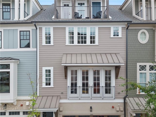 exterior space with a standing seam roof, roof with shingles, and metal roof