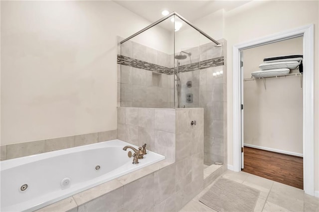 full bathroom with a whirlpool tub, a spacious closet, tile patterned flooring, and a stall shower