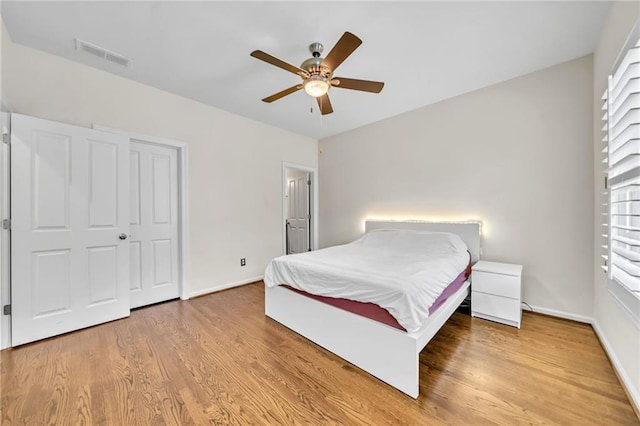 bedroom featuring baseboards, wood finished floors, visible vents, and a ceiling fan