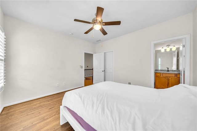 bedroom featuring light wood-type flooring, a ceiling fan, baseboards, and connected bathroom