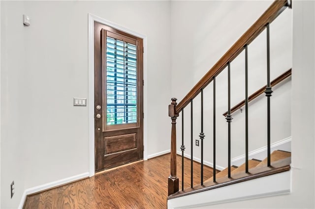 foyer featuring baseboards, wood finished floors, and stairs