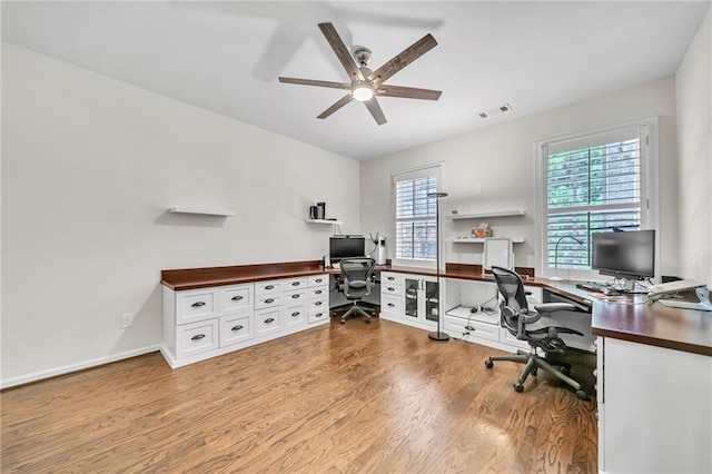 office space with baseboards, wood finished floors, visible vents, and ceiling fan