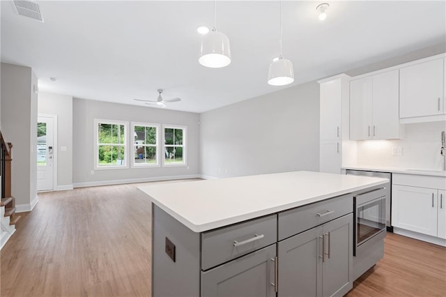 kitchen featuring ceiling fan, a kitchen island, gray cabinetry, white cabinetry, and light hardwood / wood-style floors