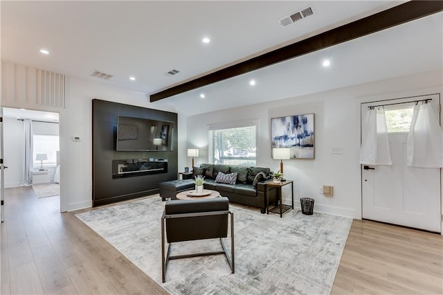 living room with light hardwood / wood-style floors and beamed ceiling