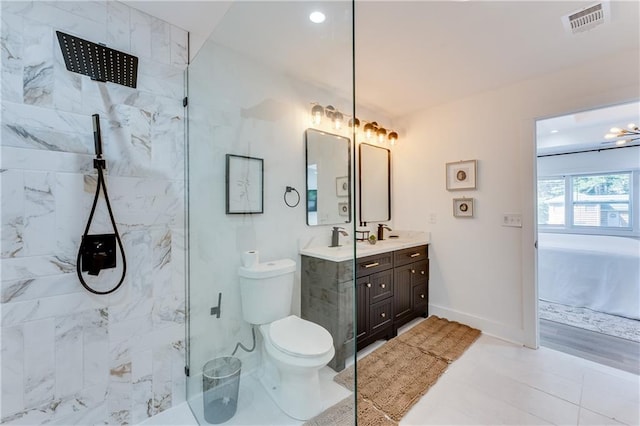 bathroom featuring toilet, vanity, tile patterned floors, and a tile shower