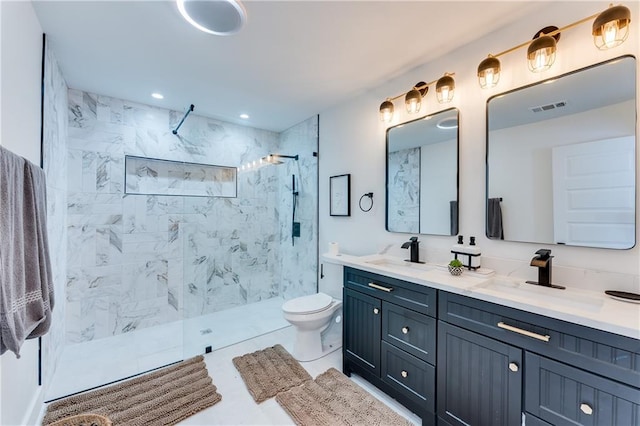 bathroom featuring toilet, vanity, tile patterned floors, and a tile shower