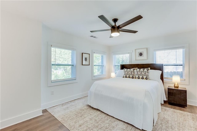 bedroom with light wood-type flooring, multiple windows, and ceiling fan