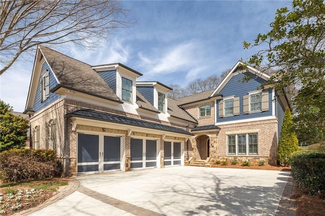 view of front facade with brick siding, a standing seam roof, concrete driveway, and a garage