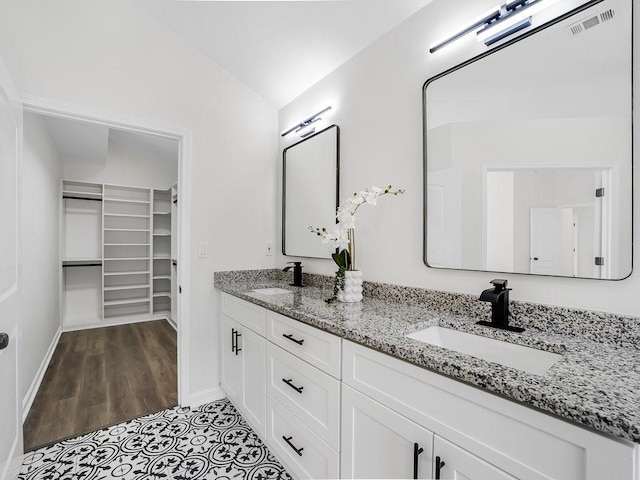 3100 Mount Gilead Rd SW, Atlanta, GA 30311 - bathroom with double vanity, vaulted ceiling, a spacious closet, and wood finished floors