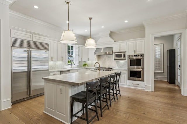 2671 Bohler Rd NW, Atlanta, GA 30327 - kitchen featuring built in appliances, light countertops, white cabinetry, wall chimney range hood, and backsplash