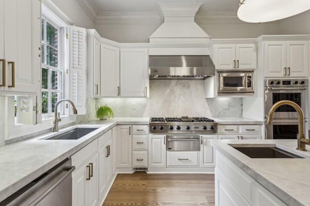 2671 Bohler Rd NW, Atlanta, GA 30327 - kitchen featuring appliances with stainless steel finishes, wall chimney exhaust hood, white cabinets, wood finished floors, and crown molding