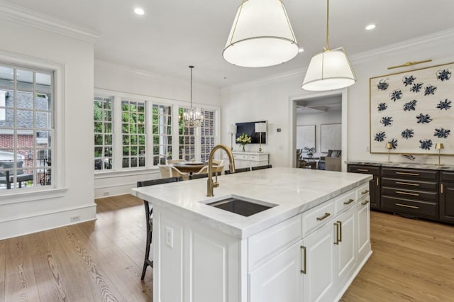 2671 Bohler Rd NW, Atlanta, GA 30327 - kitchen with light wood-style floors, white cabinetry, light stone countertops, ornamental molding, and hanging light fixtures