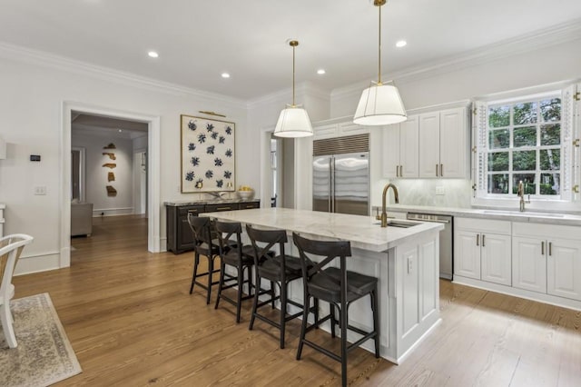 2671 Bohler Rd NW, Atlanta, GA 30327 - kitchen featuring appliances with stainless steel finishes, a kitchen island with sink, white cabinetry, a breakfast bar area, and light wood finished floors