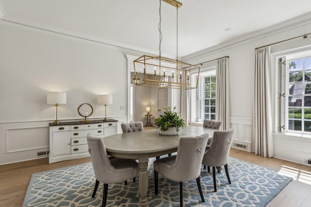 2671 Bohler Rd NW, Atlanta, GA 30327 - dining space featuring a chandelier, a decorative wall, light wood-style flooring, a wainscoted wall, and ornamental molding