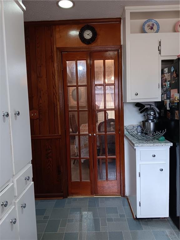 kitchen with light stone counters, a textured ceiling, and white cabinets