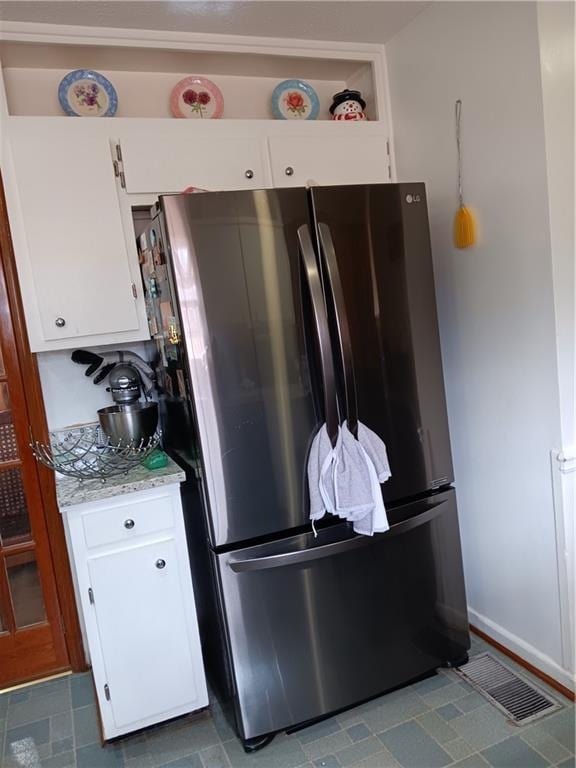 kitchen featuring white cabinets and stainless steel refrigerator