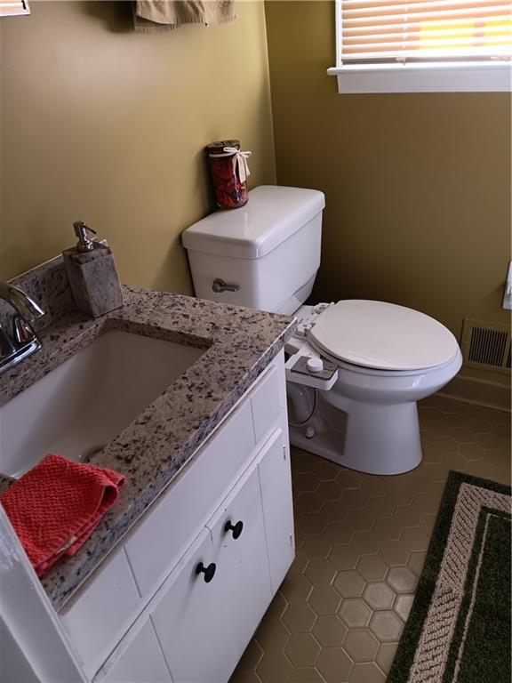 bathroom with toilet, tile patterned floors, and vanity