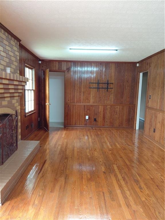 2479 Kingsland Dr, Dunwoody, GA 30360 - unfurnished living room with wooden walls, a fireplace, crown molding, wood finished floors, and a textured ceiling