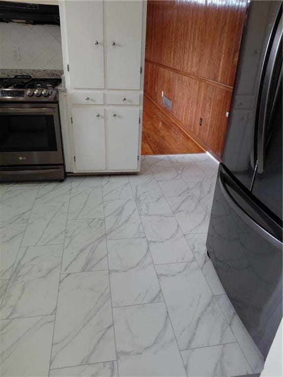 2479 Kingsland Dr, Dunwoody, GA 30360 - kitchen with stainless steel range with gas cooktop, freestanding refrigerator, ventilation hood, white cabinetry, and light marble finish floors