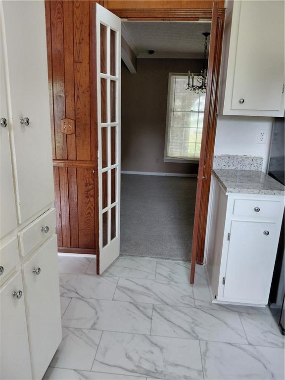 2479 Kingsland Dr, Dunwoody, GA 30360 - kitchen featuring light marble finish floors, white cabinets, a chandelier, light stone countertops, and baseboards