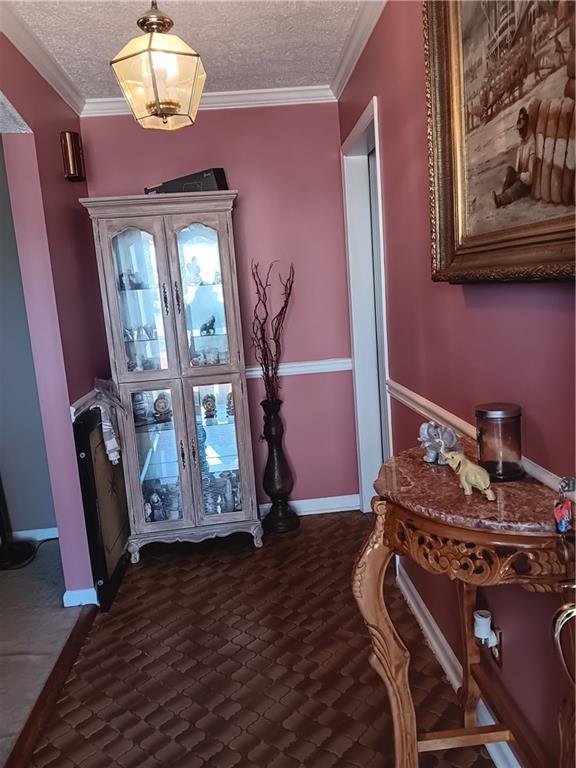 foyer entrance featuring a textured ceiling and ornamental molding