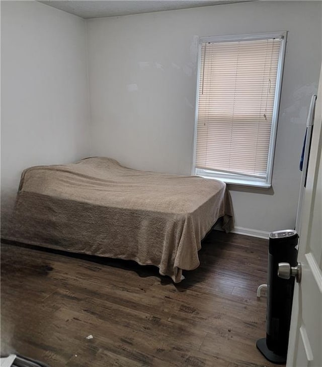 bedroom featuring baseboards and dark wood-type flooring