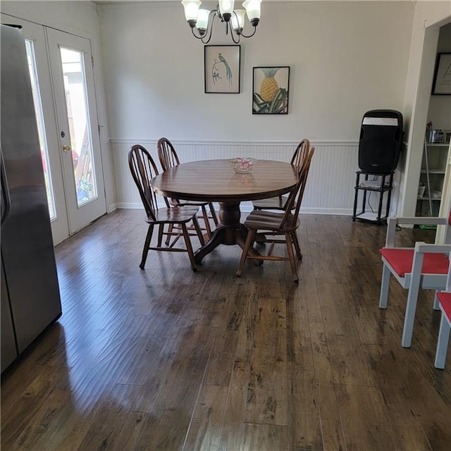 dining area with french doors, a chandelier, a wainscoted wall, and hardwood / wood-style flooring