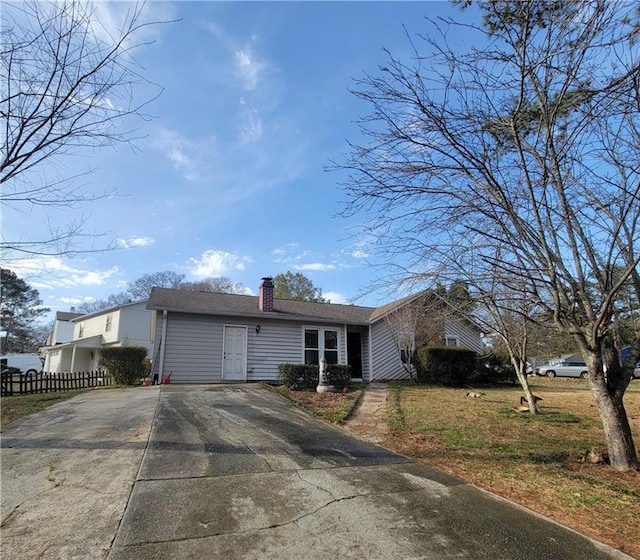 single story home featuring a chimney and fence