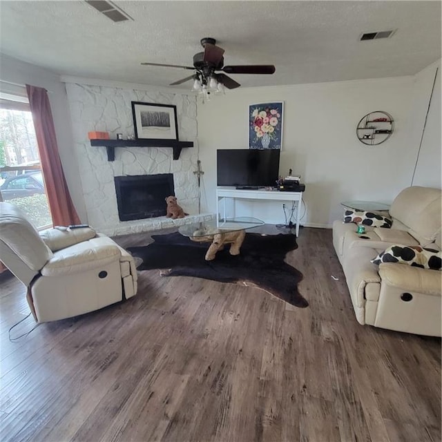 living room with a fireplace, wood finished floors, visible vents, and a textured ceiling