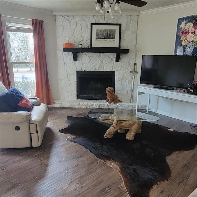 living room featuring ceiling fan, a fireplace, wood finished floors, and crown molding