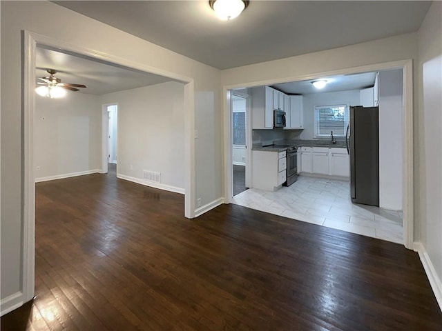 kitchen with appliances with stainless steel finishes, ceiling fan, light hardwood / wood-style floors, sink, and white cabinetry