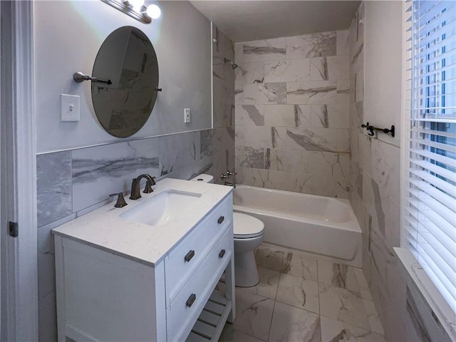 full bathroom with tile walls, tiled shower / bath combo, vanity, and toilet