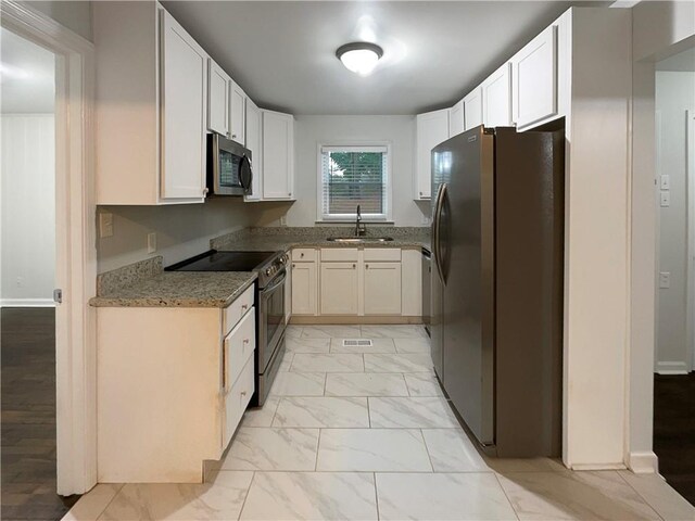 kitchen featuring dark stone countertops, white cabinetry, stainless steel appliances, and sink