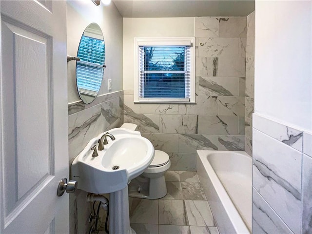 bathroom with tile walls, sink, toilet, and a bathing tub