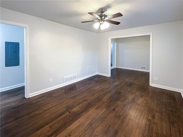empty room featuring ceiling fan, electric panel, and dark hardwood / wood-style flooring
