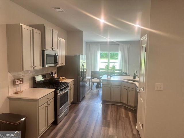 kitchen with appliances with stainless steel finishes, decorative backsplash, sink, and dark hardwood / wood-style flooring