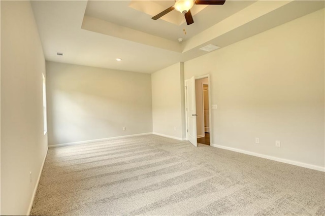 carpeted empty room featuring a tray ceiling and ceiling fan