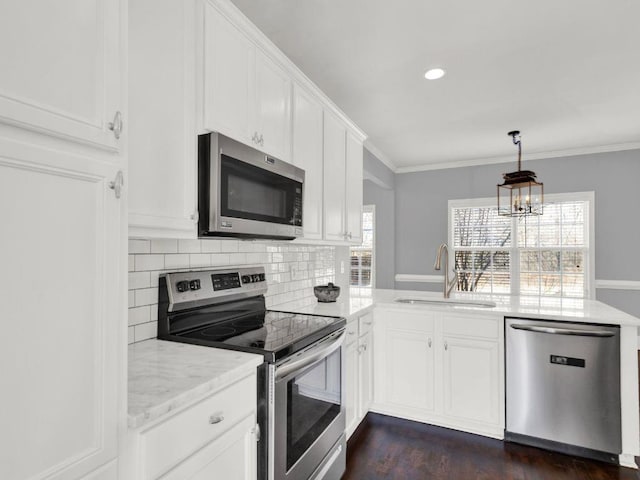 kitchen with decorative backsplash, a sink, white cabinets, a peninsula, and stainless steel appliances