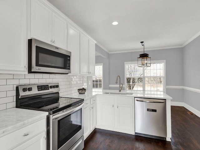 kitchen featuring appliances with stainless steel finishes, a sink, a peninsula, decorative backsplash, and ornamental molding