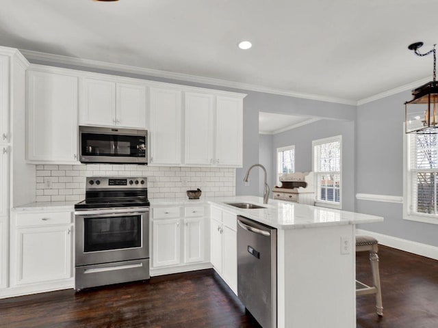 kitchen featuring a peninsula, appliances with stainless steel finishes, a sink, and tasteful backsplash