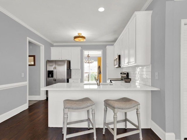 kitchen featuring decorative backsplash, a peninsula, white cabinetry, a sink, and appliances with stainless steel finishes