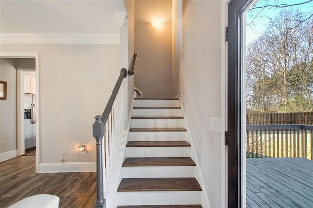 stairway featuring baseboards, ornamental molding, and wood finished floors