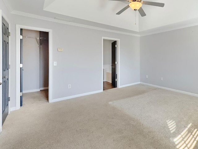 unfurnished bedroom featuring a closet, ornamental molding, baseboards, a spacious closet, and carpet flooring