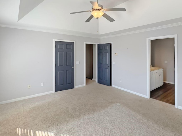 unfurnished bedroom featuring ceiling fan, crown molding, baseboards, ensuite bathroom, and carpet flooring