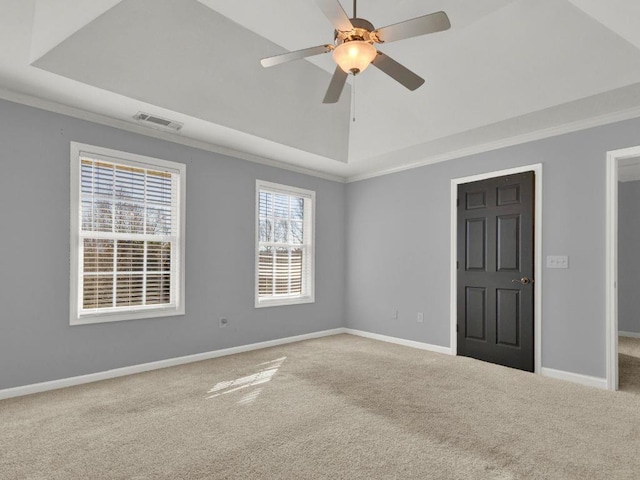 carpeted empty room with visible vents, baseboards, crown molding, and a tray ceiling