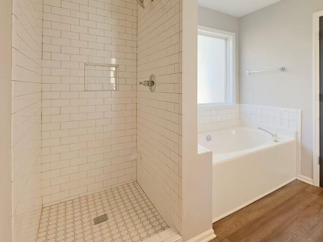 bathroom featuring a shower stall, wood finished floors, and a garden tub