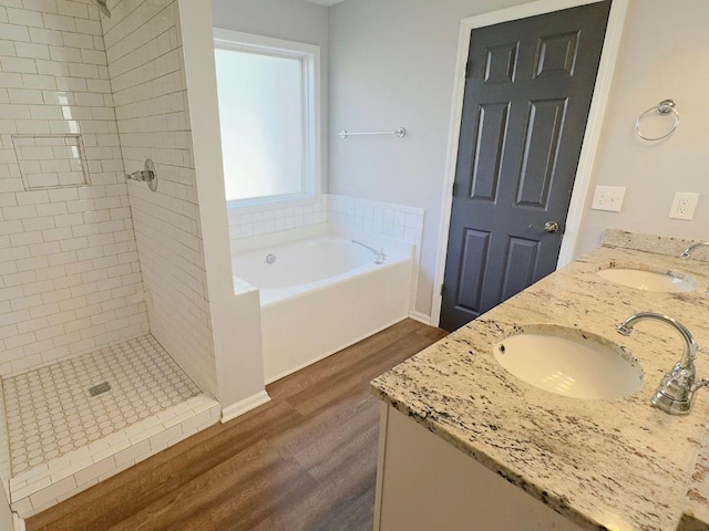 bathroom featuring a stall shower, a sink, a bath, and wood finished floors