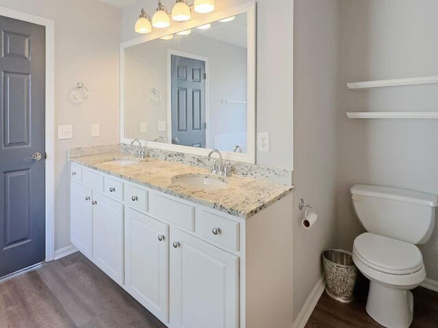 full bath featuring a sink, baseboards, toilet, and wood finished floors