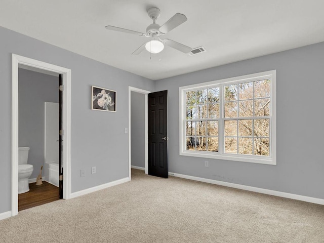 unfurnished bedroom featuring baseboards, carpet flooring, ensuite bath, and visible vents