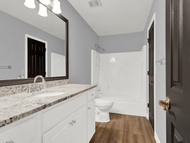 full bath featuring visible vents, vanity, wood finished floors, toilet, and  shower combination